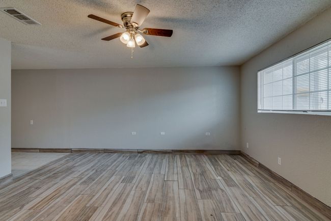 Spare room featuring a textured ceiling, visible vents, light wood-style floors, baseboards, and a ceiling fan | Image 18
