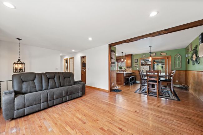 Living area with light wood finished floors, recessed lighting, a chandelier, wood walls, and wainscoting | Image 5