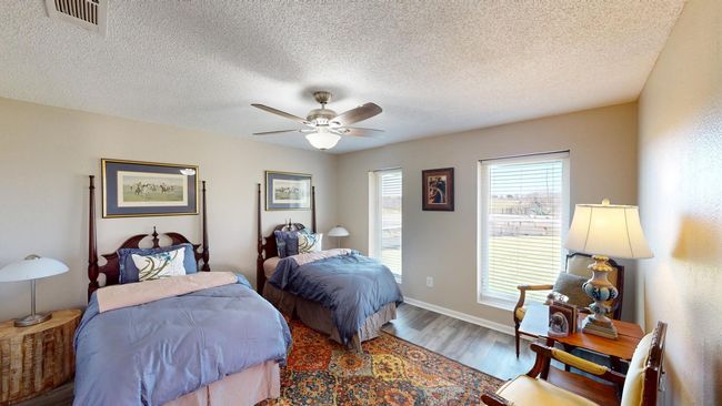 Guest Quarters Bedroom with visible vents, ceiling fan, a textured ceiling, wood finished floors, and baseboards | Image 25
