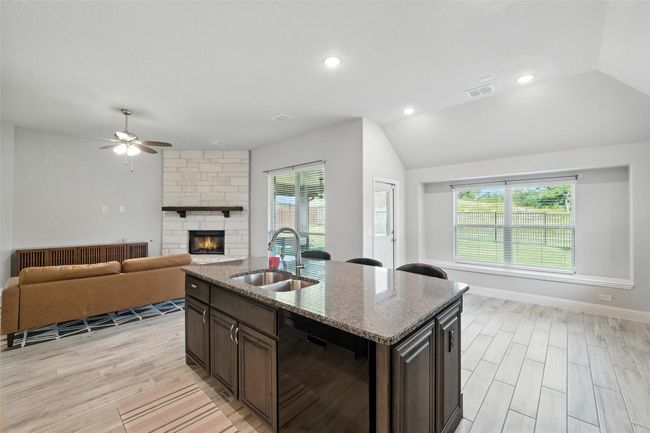 Kitchen with dishwasher, a ceiling fan, open floor plan, lofted ceiling, and a stone fireplace | Image 16