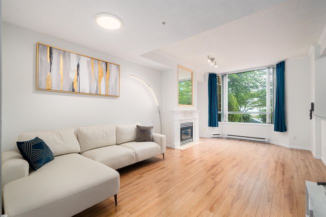 Living area with light wood finished floors, baseboard heating, and a fireplace with flush hearth | Image 6