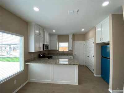 Apt.#1 Kitchen with a wealth of natural light, white cabinetry, kitchen peninsula, and stainless steel appliances | Image 2