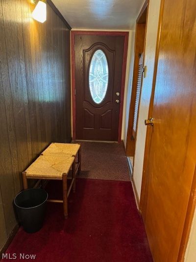 Doorway with wood walls and dark carpet | Image 2