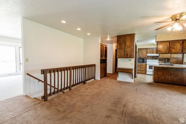 Kitchen with electric stove, light colored carpet, under cabinet range hood, recessed lighting, and ceiling fan | Image 10