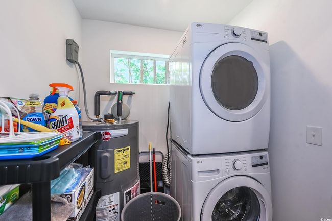 Washroom featuring electric water heater and stacked washer / dryer | Image 12