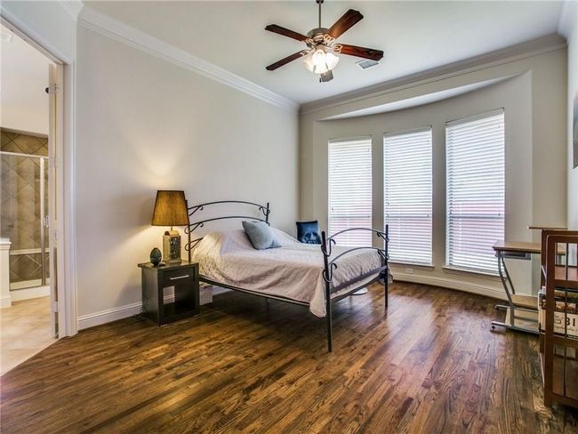 Bedroom featuring wood finished floors, multiple windows, crown molding, and baseboards | Image 12