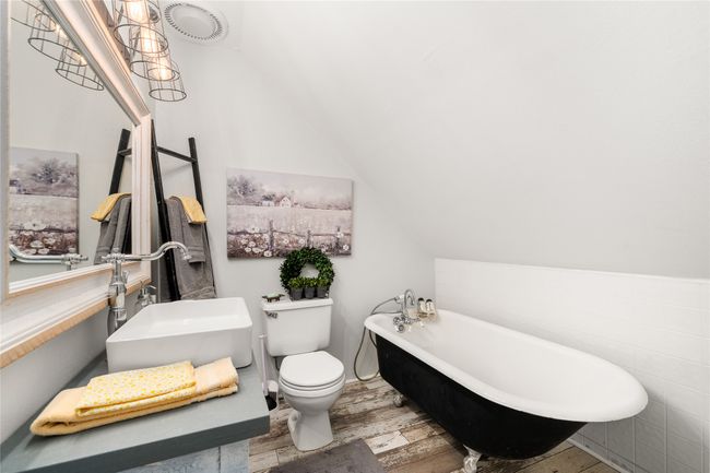 Bathroom featuring wood finished floors, a freestanding tub, and vaulted ceiling | Image 22