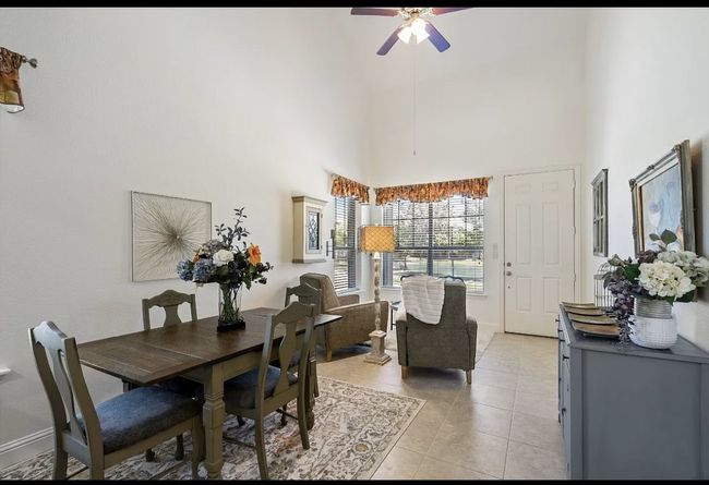 Dining space with light tile patterned floors, a ceiling fan, and a towering ceiling | Image 8