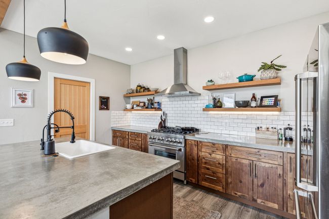 Kitchen featuring ventilation hood, high end stainless steel range, a sink, open shelves, and backsplash | Image 22