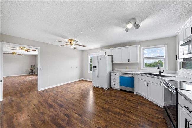 Kitchen with stainless steel microwave, white refrigerator with ice dispenser, a sink, electric range oven, and dishwashing machine | Image 60