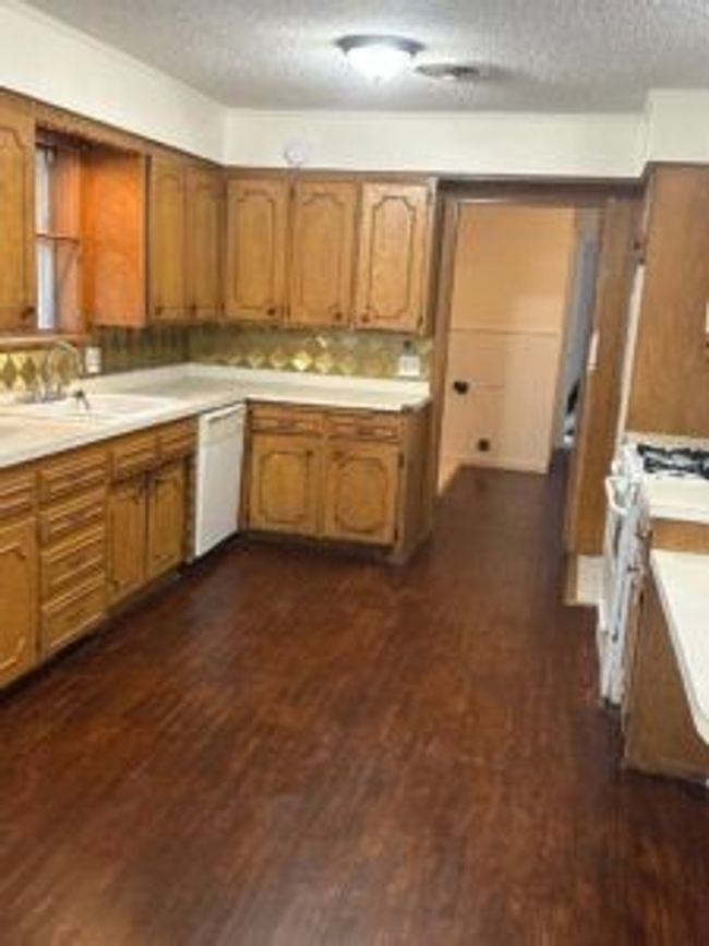 Kitchen featuring white appliances, brown cabinetry, light countertops, a textured ceiling, and dark wood finished floors | Image 12
