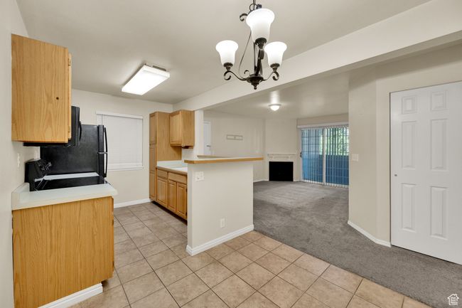 Kitchen featuring open floor plan, range with electric stovetop, light tile patterned floors, light countertops, and a chandelier | Image 12