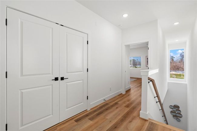 A second-floor landing with recessed lighting, premium wood flooring, and a functional layout for easy access to bedrooms and storage. | Image 14