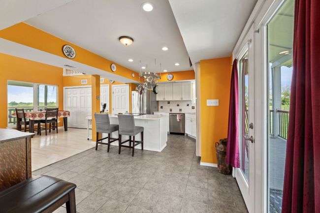 Kitchen with white cabinets, light countertops, a breakfast bar, appliances with stainless steel finishes, and a center island | Image 8