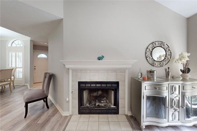 Living area featuring wood finished floors, a tiled fireplace, and baseboards | Image 8