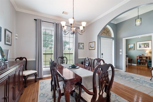 Dining area featuring arched walkways, crown molding, a chandelier, and light wood-style flooring | Image 9