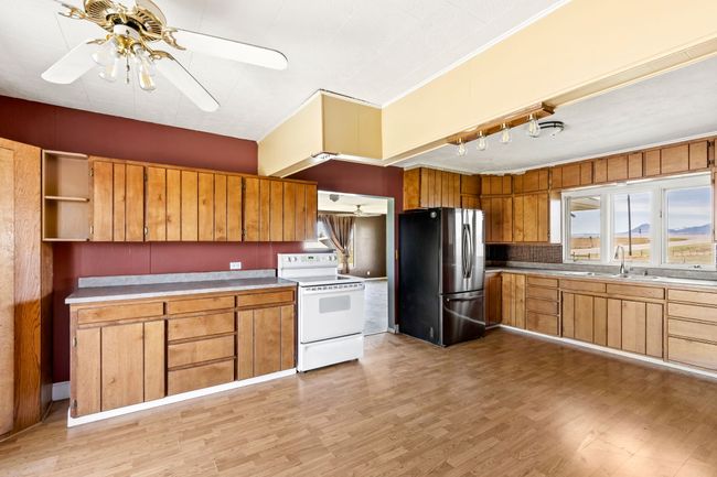Kitchen featuring a sink, ceiling fan, track lighting, white electric stove, and freestanding refrigerator | Image 24