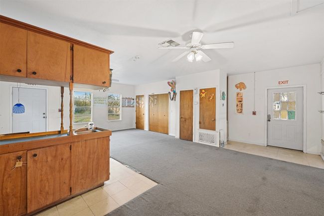 Kitchen featuring a ceiling fan, visible vents, light tile patterned flooring, light carpet, and brown cabinets | Image 18