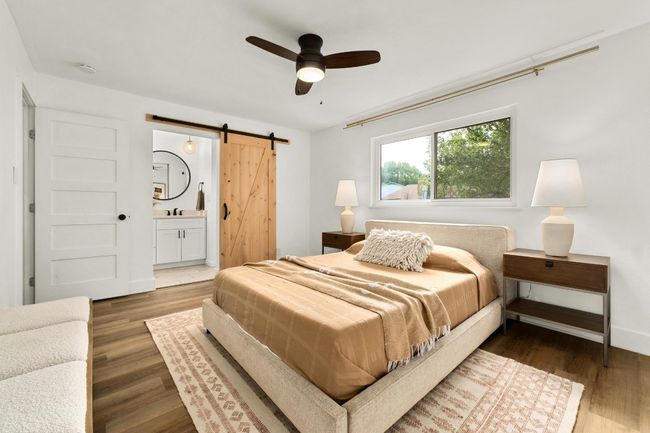 Bedroom with a barn door, wood finished floors, ensuite bath, and a ceiling fan | Image 12