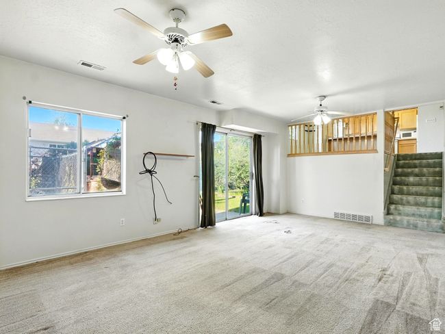 Unfurnished living room featuring ceiling fan, stairway, carpet, and a textured ceiling | Image 10
