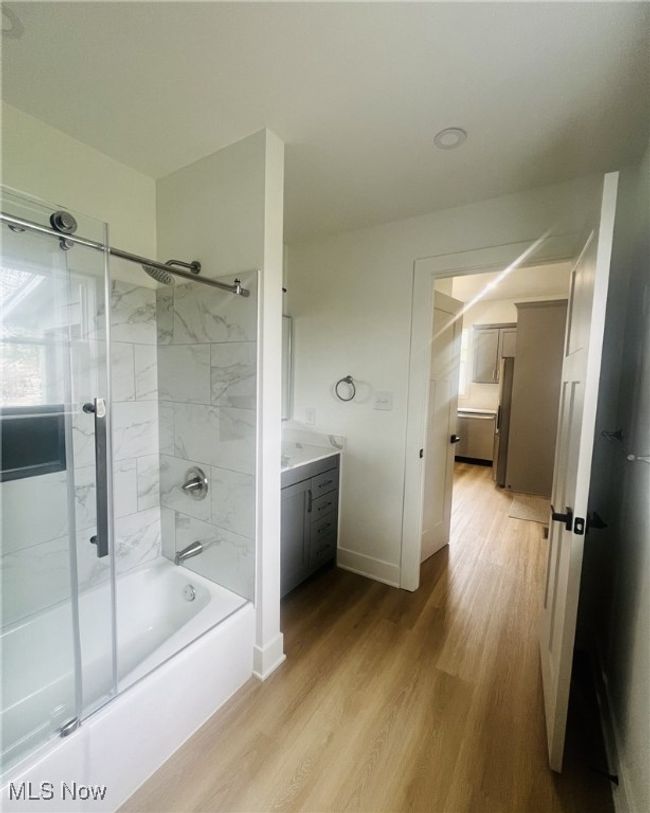 Bathroom with baseboards, vanity, wood finished floors, and bath / shower combo with glass door | Image 12