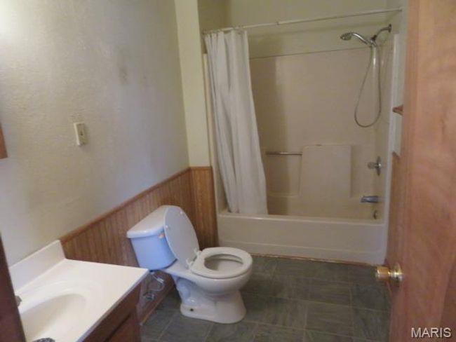 Full bathroom featuring shower / bath combination with curtain, toilet, and vanity | Image 7