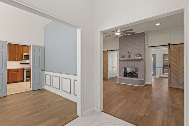 Unfurnished living room with a decorative wall, a towering ceiling, a barn door, and ceiling fan | Image 4