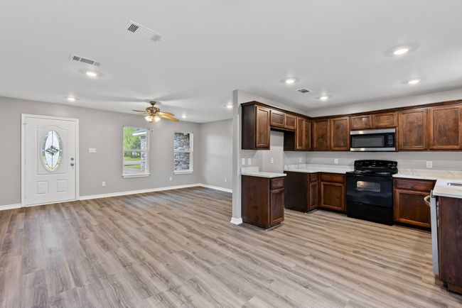 Kitchen featuring black range with electric cooktop, stainless steel microwave, recessed lighting, light countertops, and light wood-type flooring | Image 8