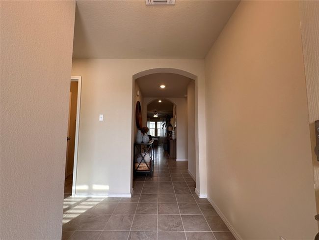 Hallway with arched walkways, tile patterned floors, and baseboards | Image 4