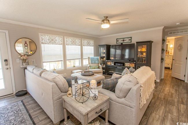 Living room featuring wood finished floors, a ceiling fan, visible vents, and crown molding | Image 17