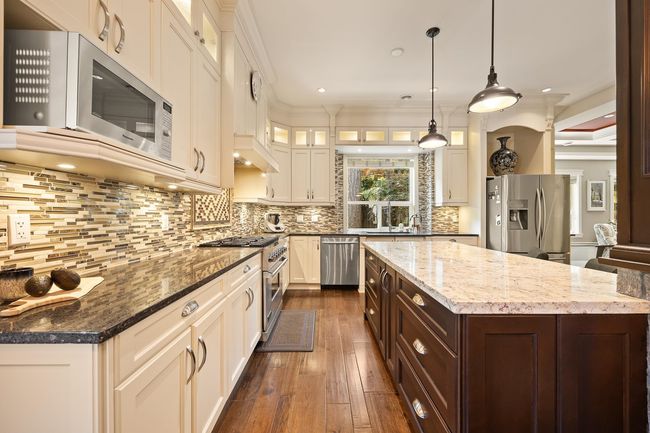 Kitchen featuring stainless steel appliances, dark brown cabinets, dark wood finished floors, glass insert cabinets, and ornamental molding | Image 10
