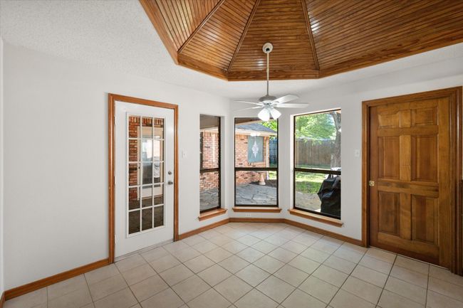 The breakfast nook looks out to the backyard. There is a door leading to a covered, flagstone patio. A wall of windows streams natural light. | Image 24
