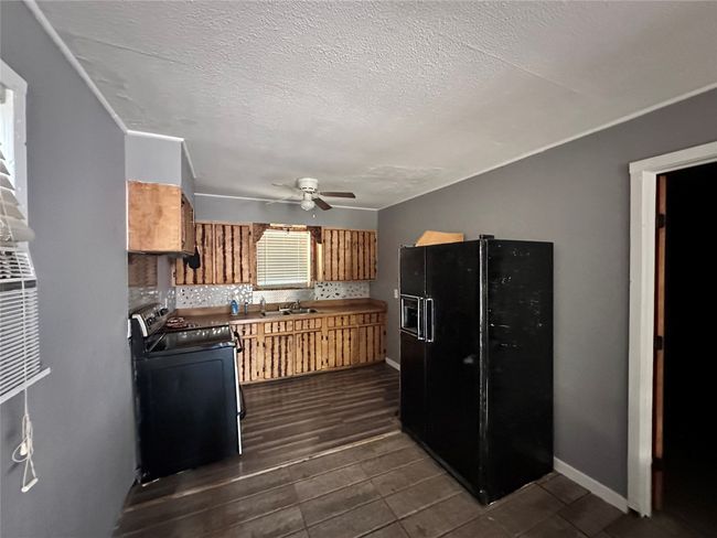 Kitchen featuring stove, black fridge, a ceiling fan, a sink, and a textured ceiling | Image 6