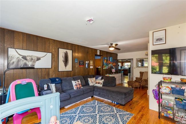 Living area featuring wooden walls, wood finished floors, and a ceiling fan | Image 7