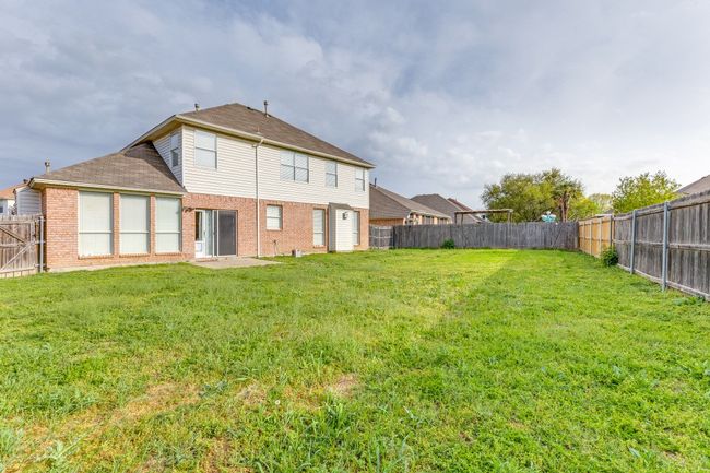 Rear view of house featuring brick siding, a fenced backyard, and a yard | Image 25