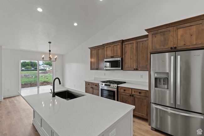 Kitchen with stainless steel appliances, a sink, vaulted ceiling, a chandelier, and light wood finished floors | Image 5