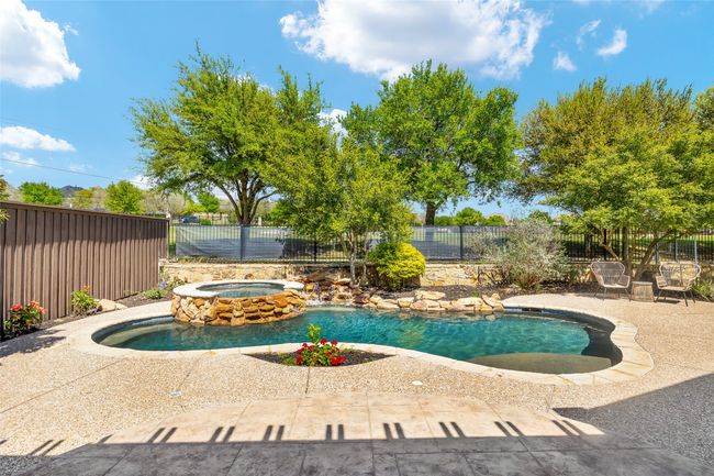 View of pool with a patio area, a pool with connected hot tub, and a fenced backyard | Image 26