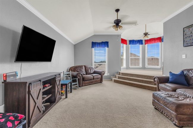 Living room with lofted ceiling, crown molding, ceiling fan, and carpet | Image 24