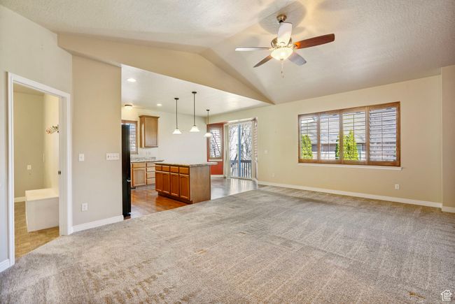 Unfurnished living room with baseboards, vaulted ceiling, dark colored carpet, and a ceiling fan | Image 10