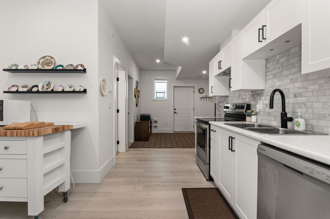 Kitchen featuring appliances with stainless steel finishes, open shelves, a sink, white cabinets, and recessed lighting | Image 29