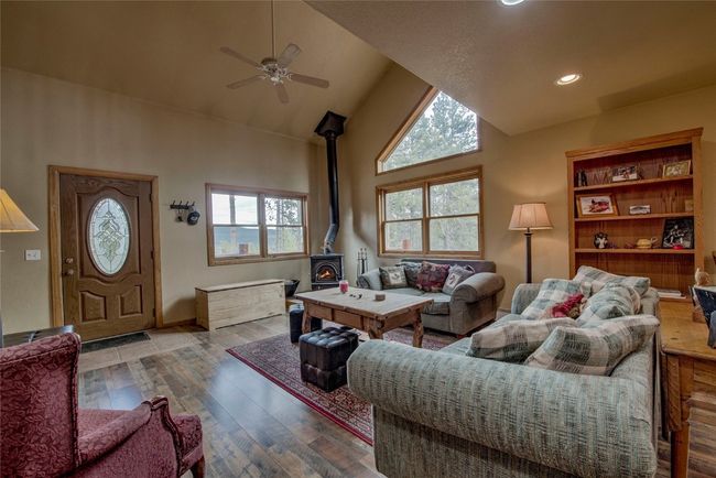 Living area featuring high vaulted ceiling, a wood stove, a ceiling fan, wood finished floors, and recessed lighting | Image 10