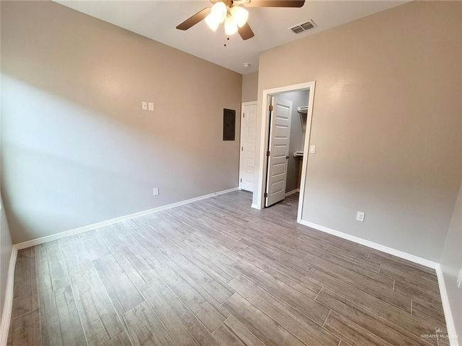 Empty room featuring a ceiling fan, wood finished floors, and electric panel | Image 11