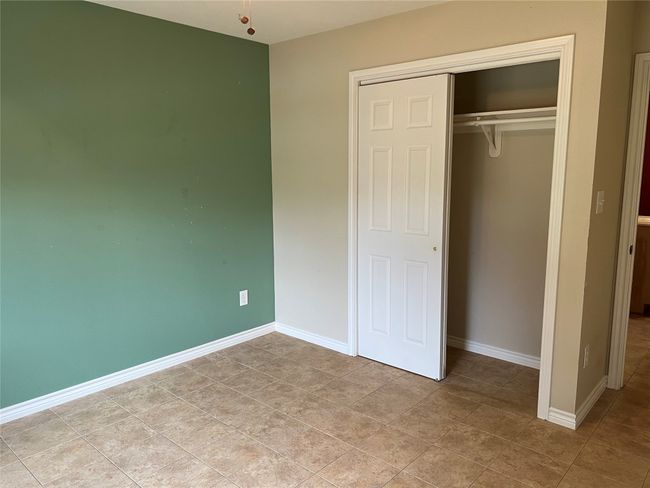 Unfurnished bedroom with a closet, baseboards, and light tile patterned flooring | Image 10