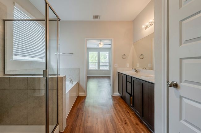 Bathroom featuring double vanity, a bath, visible vents, a stall shower, and wood finished floors | Image 16