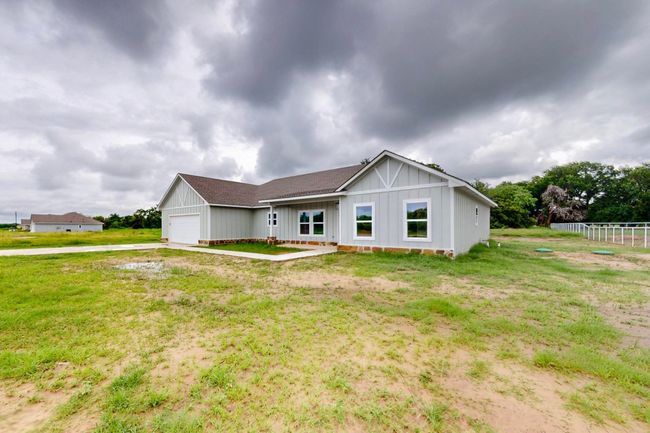 Single story home featuring a garage, board and batten siding, driveway, and roof with shingles | Image 9