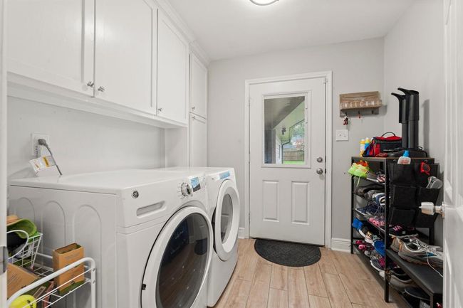 Laundry room with ample cabinet storage, organized shelving for shoes and essentials and access to the backyard. | Image 18