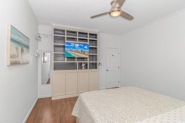 Bedroom with wood finished floors, crown molding, a textured ceiling, baseboards, and a ceiling fan | Image 19