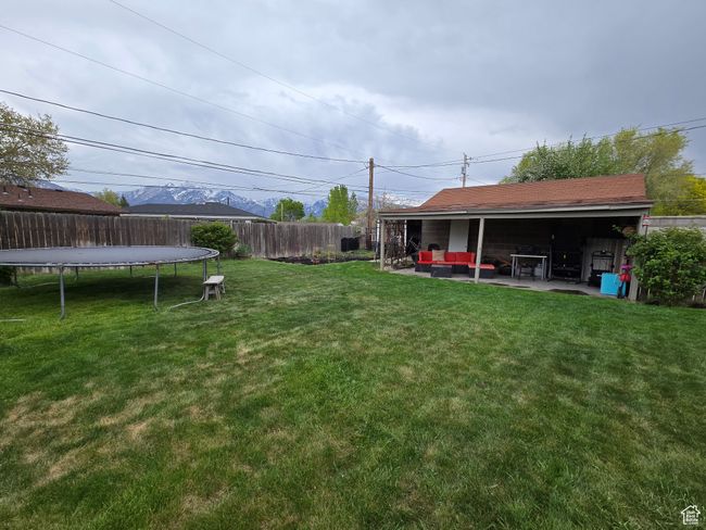 View of yard with outdoor lounge area, a trampoline, a patio area, and fence | Image 7