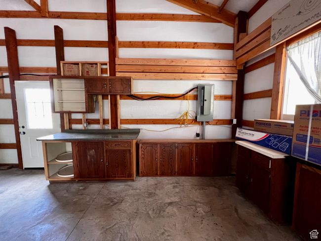 Kitchen with open shelves, unfinished concrete flooring, and electric panel | Image 26