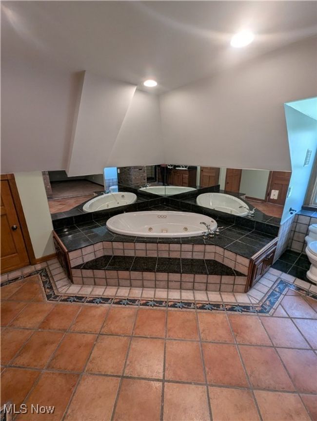 Bathroom featuring toilet and a tub with jets | Image 5